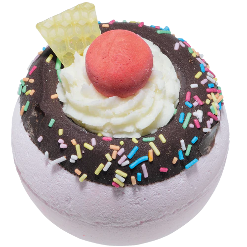 Bath bomb with chocolate, whipped cream, cherry, and sprinkles on a white background