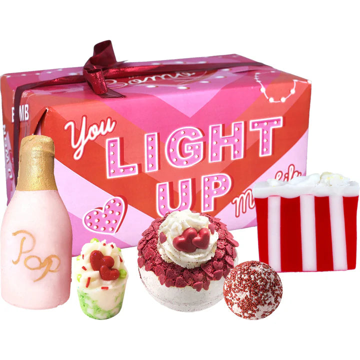 Valentine's Day gift set with 'You Light Up My Life' box, pink bottle, and small treats on a white background.